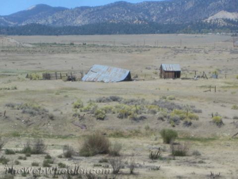 1987 Suzuki Samurai - An old barn and shed stand in a desolate landscape under a clear sky.