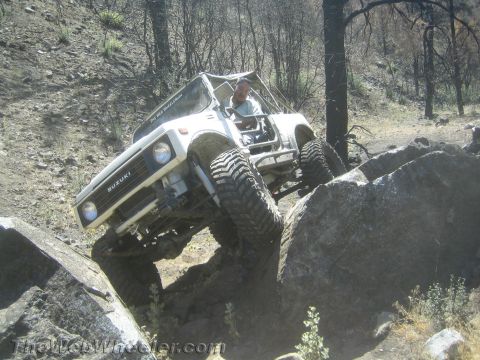 1987 Suzuki Samurai - A white 1987 Suzuki Samurai navigates a rocky trail with a driver visible.