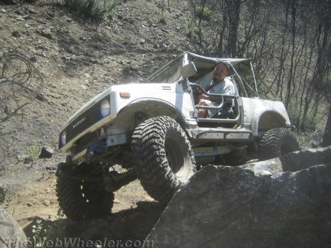 1987 Suzuki Samurai - A white 1987 Suzuki Samurai navigates a rocky trail, demonstrating its off-road capabilities.