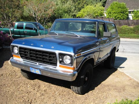 1978 Ford Bronco - A blue 1978 Ford Bronco is parked in a driveway with a green pickup truck in the background.