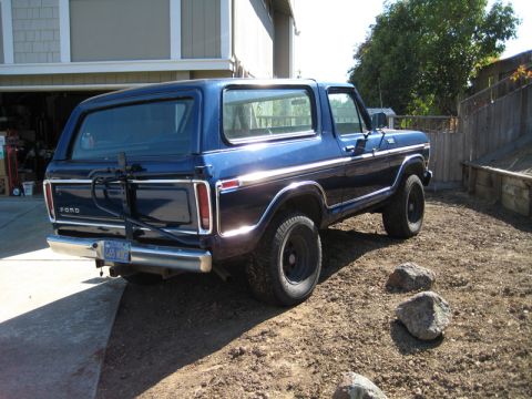 Blue 1978 Ford Bronco parked on dirt lot, rear view