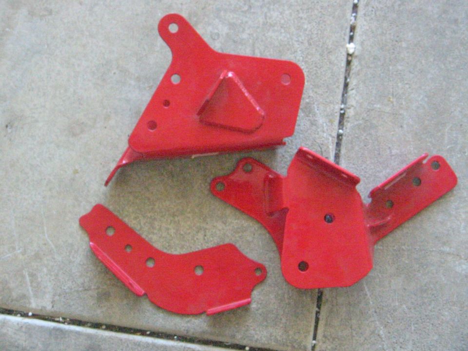 Three red metal brackets on a concrete surface