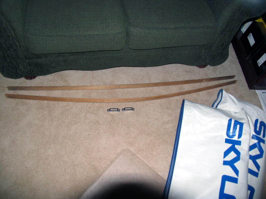 Two curved wooden soft-top bows and metal brackets laid out on carpet