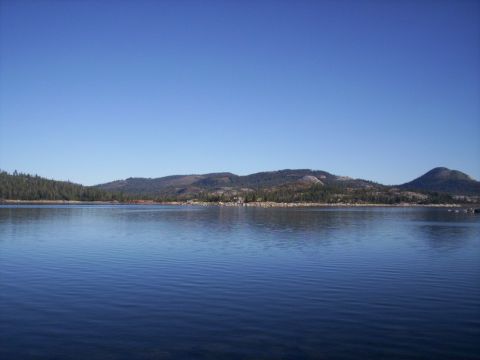 1989 Ford Bronco - A lake reflects the clear blue sky, with rolling, tree-covered hills in the distance.