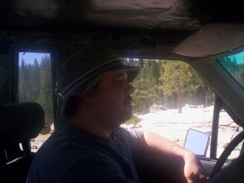 1989 Ford Bronco - Man drives an older SUV through a rocky, wooded area on a sunny day.