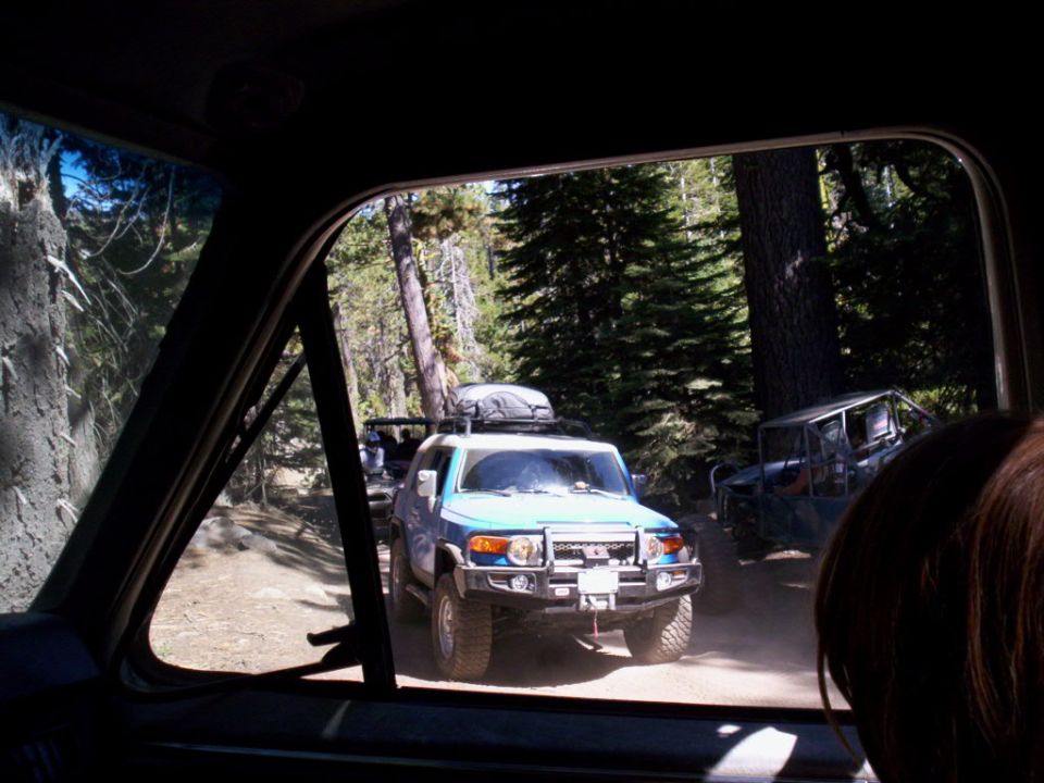Light blue Toyota FJ Cruiser with roof rack and bull bar on a dirt road