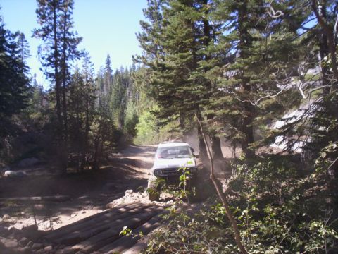 1989 Ford Bronco - SUV navigates a challenging off-road path through a forest.