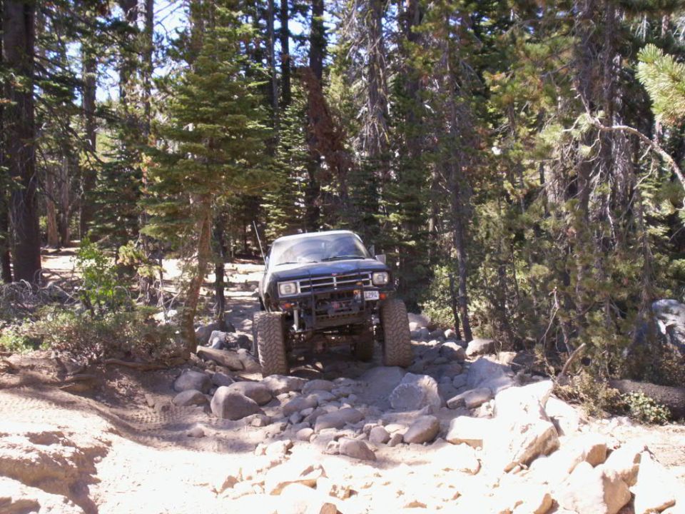 Dark blue off-road truck navigating a rocky trail, front-mounted winch visible