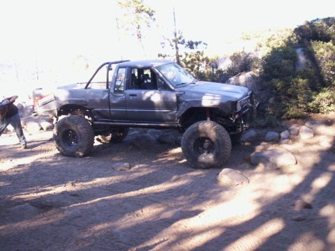 1989 Ford Bronco - Pickup truck modified for off-road use navigates a rocky trail.