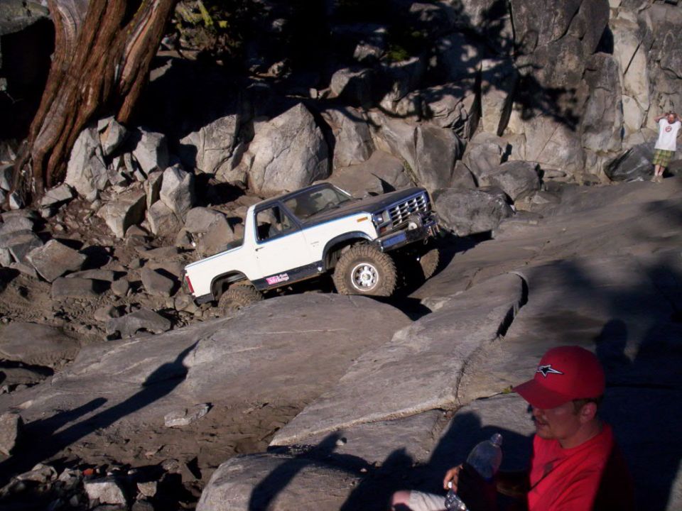 White and black SUV with off-road tires climbing rocky terrain