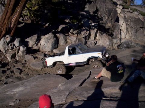 1989 Ford Bronco - A white Ford Bronco navigates a rocky trail with spectators watching.