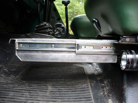 1978 Ford Bronco - Close-up of a shop-built polished aluminum storage box or drawer slide mounted on the floor beside a green vinyl seat inside a 4x4, using e…