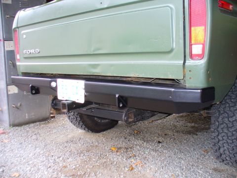 1978 Ford Bronco - Aftermarket rear bumper and trailer hitch receiver on a green vehicle.