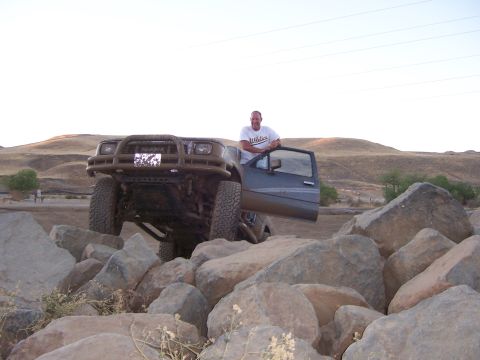 1991 Ford Bronco - Man stands in the open door of a gray SUV as it navigates a rocky obstacle course.