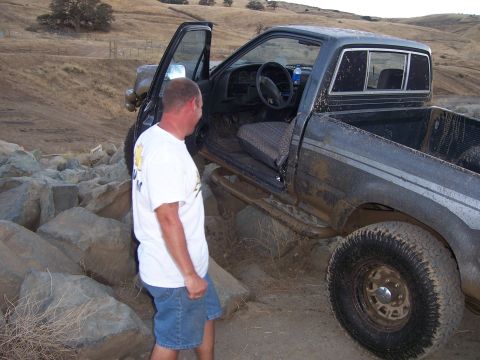 1991 Ford Bronco - Pickup truck navigating rocky terrain with driver's door open.