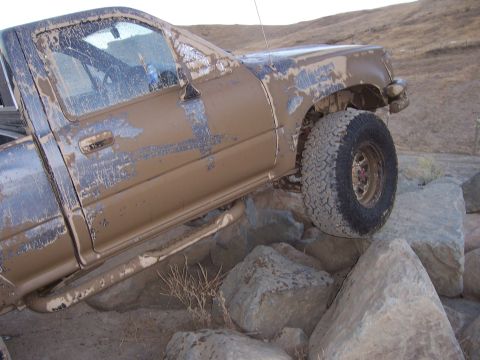 1991 Ford Bronco - This truck is covered in mud and appears to be navigating a rocky obstacle course.