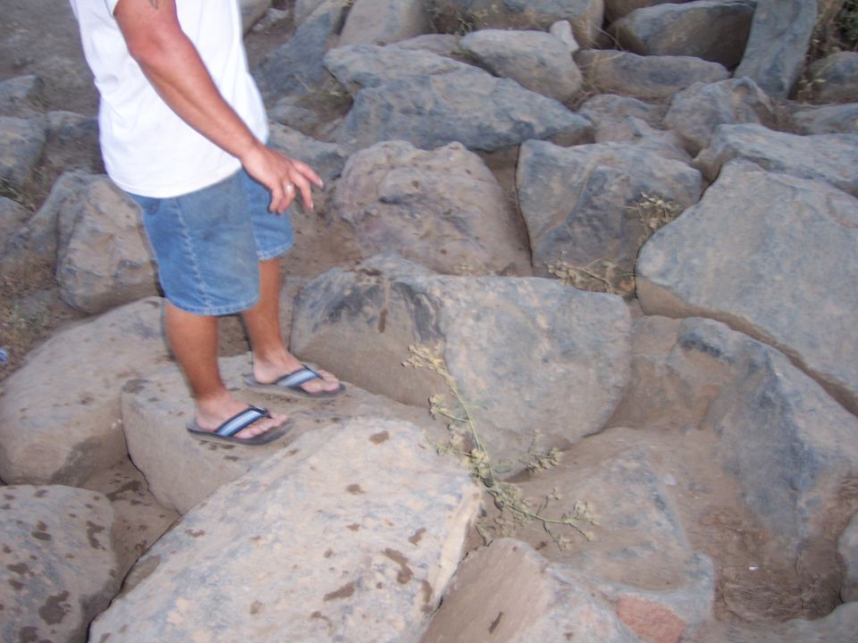 Person in shorts and flip-flops standing on large rocks