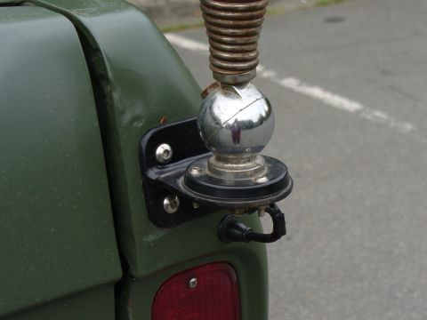 1978 Ford Bronco - Close-up of a CB antenna mount attached to the rear corner of a green vehicle, showing the spring and chrome ball.