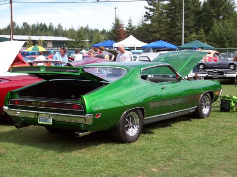 1997 Ford Mustang - A green 1970 Ford Torino GT is displayed with its trunk and hood open at an outdoor car show.