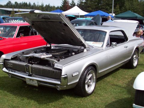 1997 Ford Mustang - A silver 1969 Mercury Cougar is displayed with its hood and trunk open at an outdoor car show.