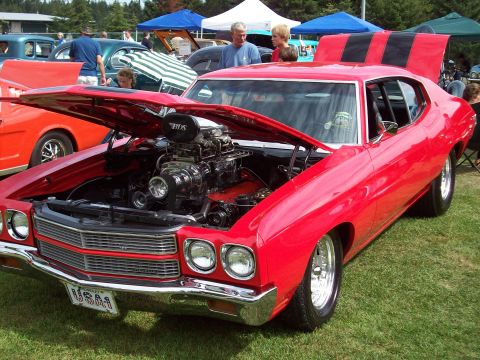 1997 Ford Mustang - A bright red muscle car is displayed with its hood open, revealing a powerful engine and custom modifications.