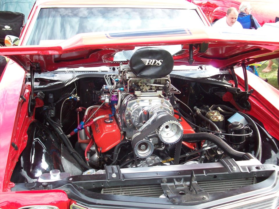 Red car engine bay with a BDS supercharger, chrome components, and red valve covers