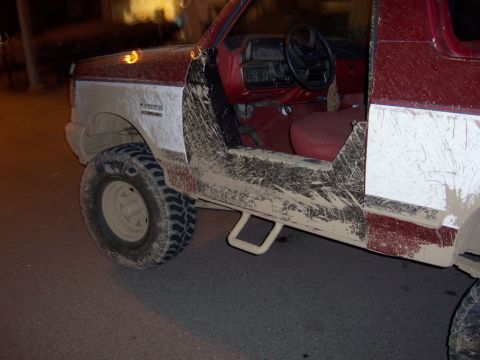 1991 Ford Bronco - Mud-covered 1991 Ford Bronco shows its interior and side panel, with visible 'Bronco' badging.