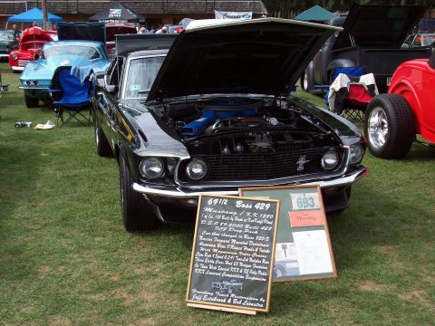 1997 Ford Mustang - A black 1969 Ford Mustang Boss 429 is displayed with its hood open at a car show, with other vehicles visible in the background.