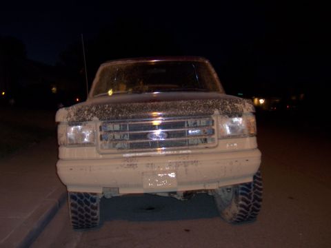 1991 Ford Bronco - Front view of a mud-caked Ford F-Series truck parked at night.