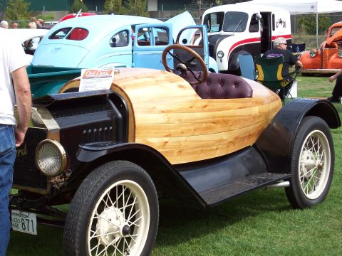 1997 Ford Mustang - This custom wood-bodied car is displayed alongside other vintage vehicles at an outdoor event.