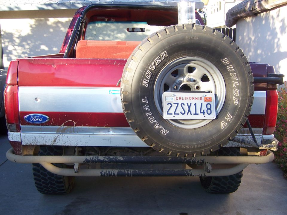 Red 1991 Ford Bronco rear view with spare tire mounted externally, California license plate 2ZSX148