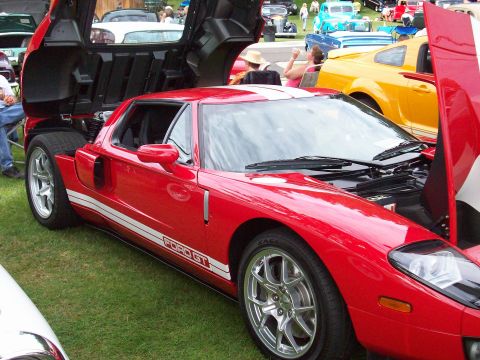 1997 Ford Mustang - A red Ford GT with its doors and hood open is displayed at an outdoor car show.