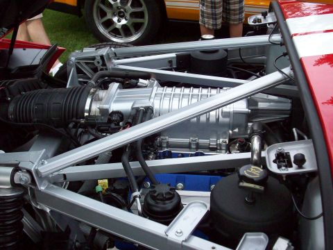 1997 Ford Mustang - Close-up view of a supercharged engine bay, a prominent silver supercharger and red exterior accents.