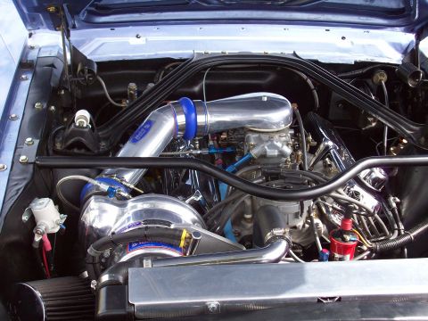 1997 Ford Mustang - The engine bay of a classic blue car, a modified engine with a turbocharger and chrome components.