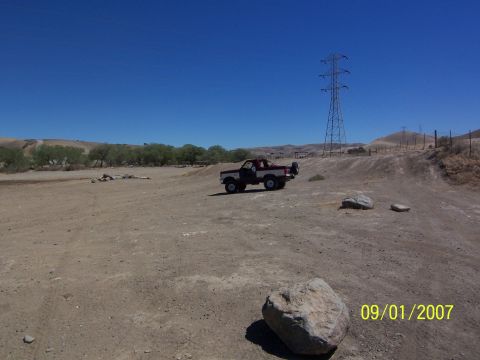 1991 Ford Bronco - A 1991 Ford Bronco sits on a dusty trail under a clear blue sky, with a large power line tower nearby.