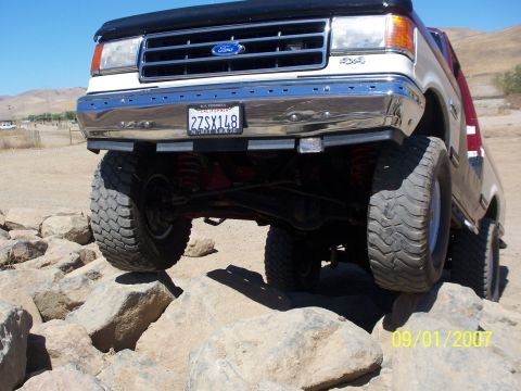1991 Ford Bronco - This 1991 Ford Bronco is shown navigating a rocky terrain, highlighting its off-road capabilities.