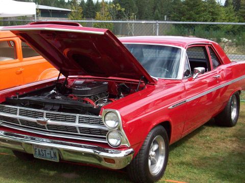 1997 Ford Mustang - A red 1967 Ford Fairlane is displayed with its hood open, revealing the engine compartment. Another vehicle is partially visible to the lef…