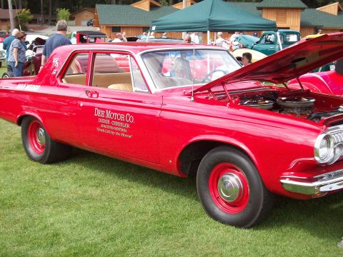 1997 Ford Mustang - A vintage red Dodge sedan is displayed on a grassy field with its hood open, revealing the engine compartment.