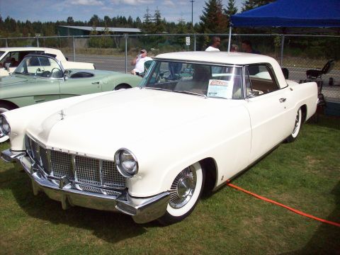 1997 Ford Mustang - A classic white Lincoln Continental Mark II is displayed at an outdoor event with other vehicles present.