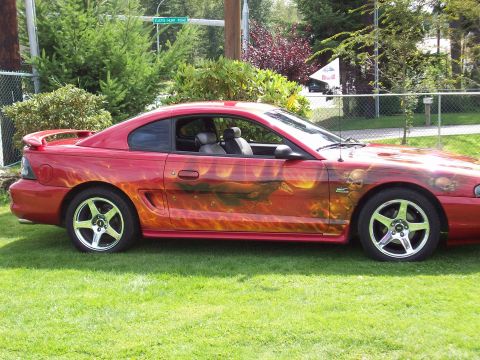 1997 Ford Mustang - This red coupe features custom flame and skull graphics on its side, with a spoiler on the rear.