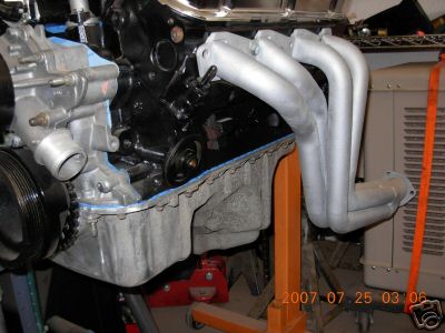 1980 Ford Bronco - Close-up of an engine block and exhaust manifold, mounted on an engine stand.