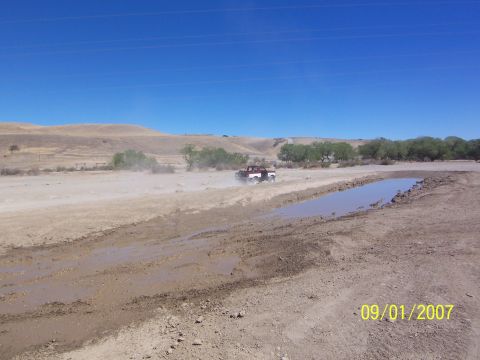 1991 Ford Bronco - Ford Bronco navigating a dirt track with a water hazard on a clear day.
