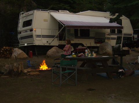 1986 Ford Bronco - A campsite scene features a camper trailer, a campfire, and a picnic table laden with food.