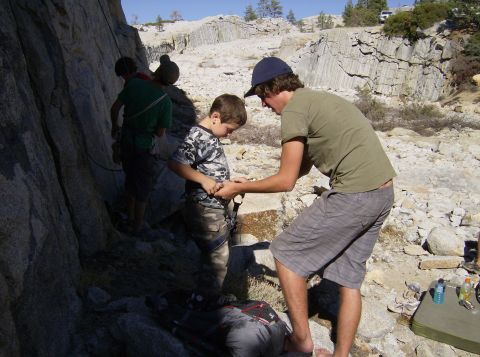 1986 Ford Bronco - Adults assist a child with climbing gear near a rocky cliff face.