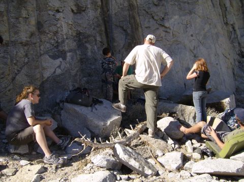 1986 Ford Bronco - A group of people are at the base of a large rock formation, possibly for rock climbing or bouldering.