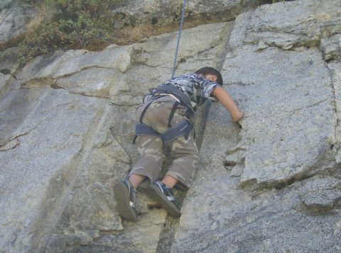 1986 Ford Bronco - A young climber scales a rocky cliff, using a rope for safety.