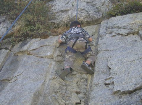 1986 Ford Bronco - A child is shown rock climbing on a large granite rock formation.