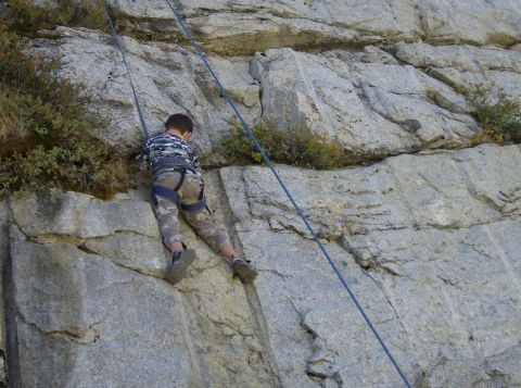 1986 Ford Bronco - A child is ascending a rock face, secured by climbing ropes and harness.
