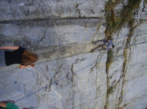 1986 Ford Bronco - Two people are rock climbing on a steep, textured rock face, secured by ropes.