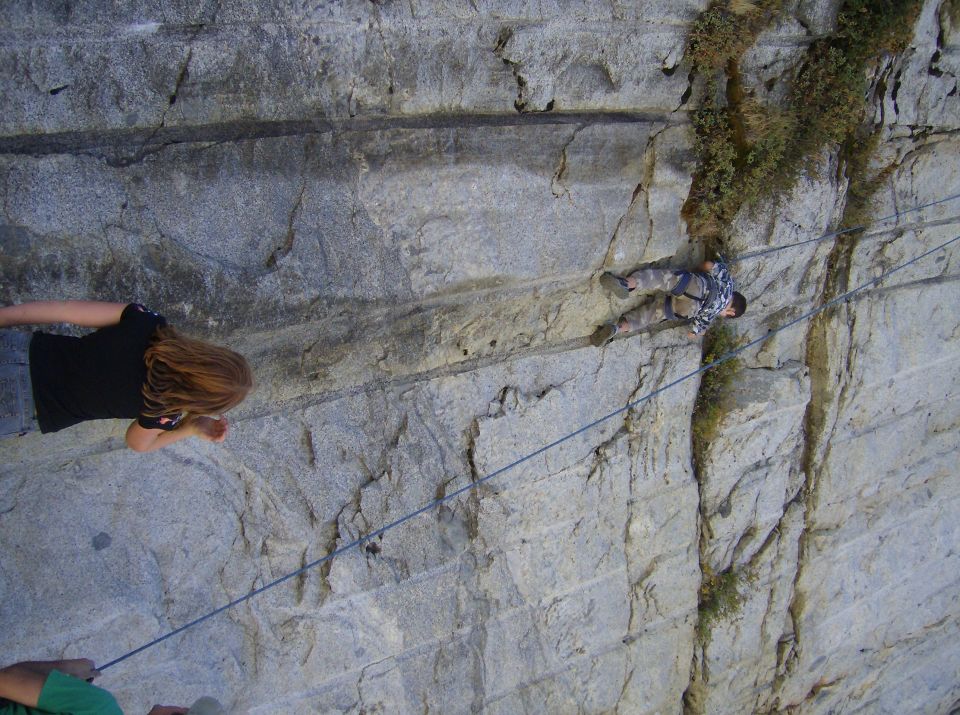 People rock climbing on a large rock face with ropes
